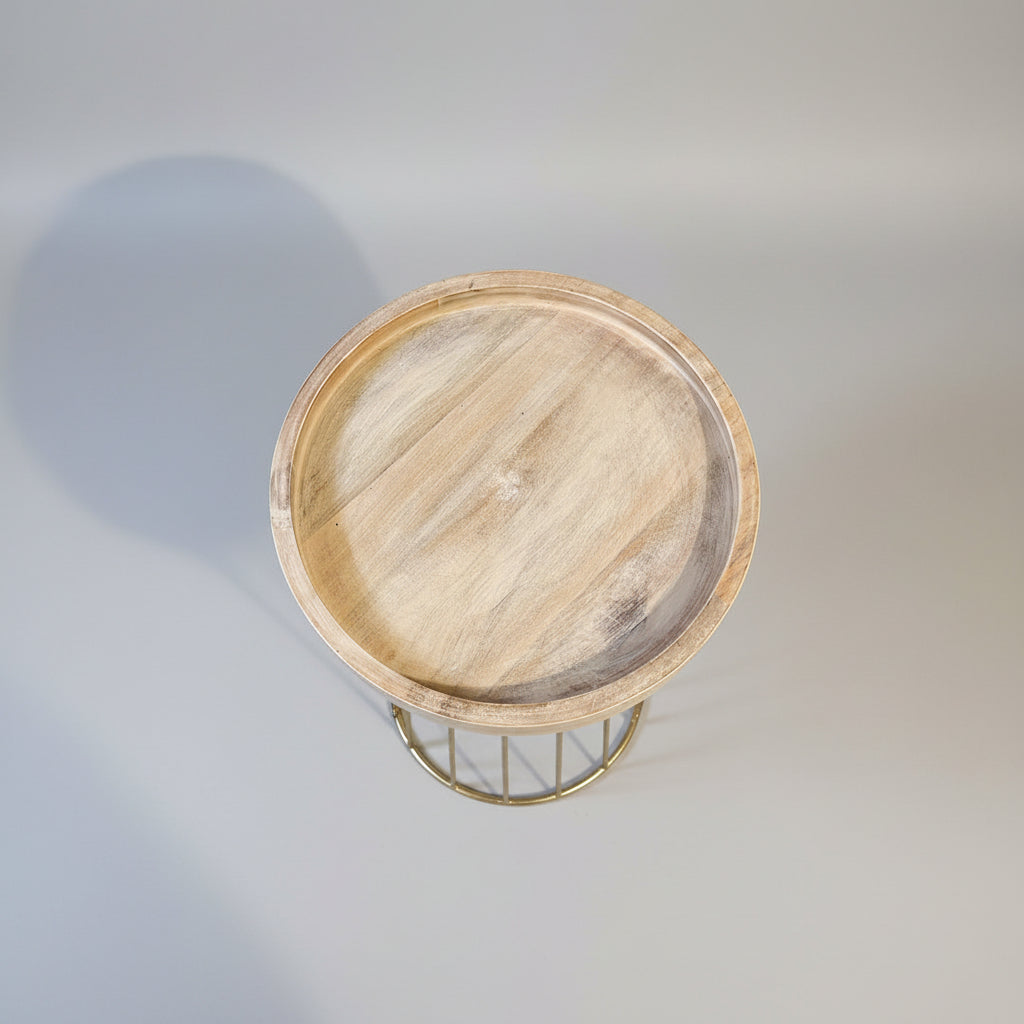 A round wooden serving tray with a natural light brown wood grain finish, shown from a top-down angle on a stone floor against a textured beige wall.